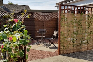 A patio with a table and chairs, a wooden fence, and a climbing plant. - Beautiful 1-bed Apartment in York (York)