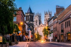 A street leading to a historic cathedral with Gothic architecture, including pointed arches and a spire. - Beautiful 1-bed Apartment in York (York)