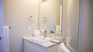 Une salle de bain équipée d’un lavabo, d’un miroir, d’un porte-serviettes et d’une porte de douche en verre.