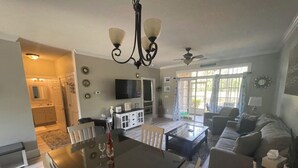 A spacious living room with a dining area, a television, and a ceiling fan. - PROMO 5% WEEKLY DISCOUNT!
New Listing Golfer Haven w/Patio Pool & Beach shuttle (North Myrtle Beach)