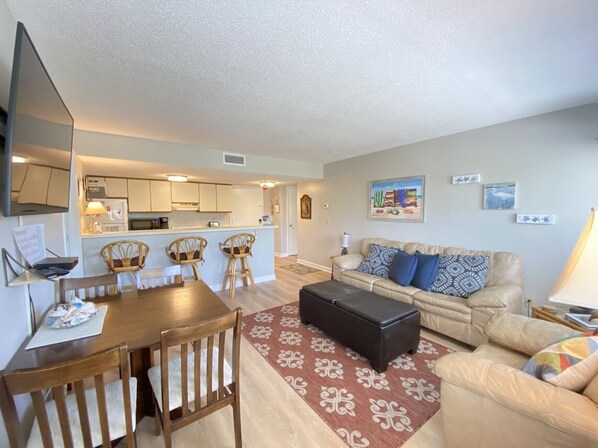 A compact living space with a dining area, kitchenette, and a sofa set.