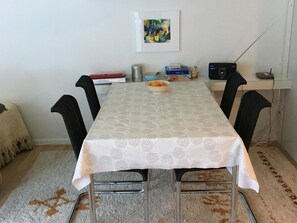 Ein Essbereich mit Tisch, Stühlen, einem Radio und einem Bild an der Wand.