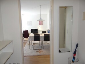 En gang der fører til et spiseområde med et bord og stole, en hængende lampe og et spejl på væggen.