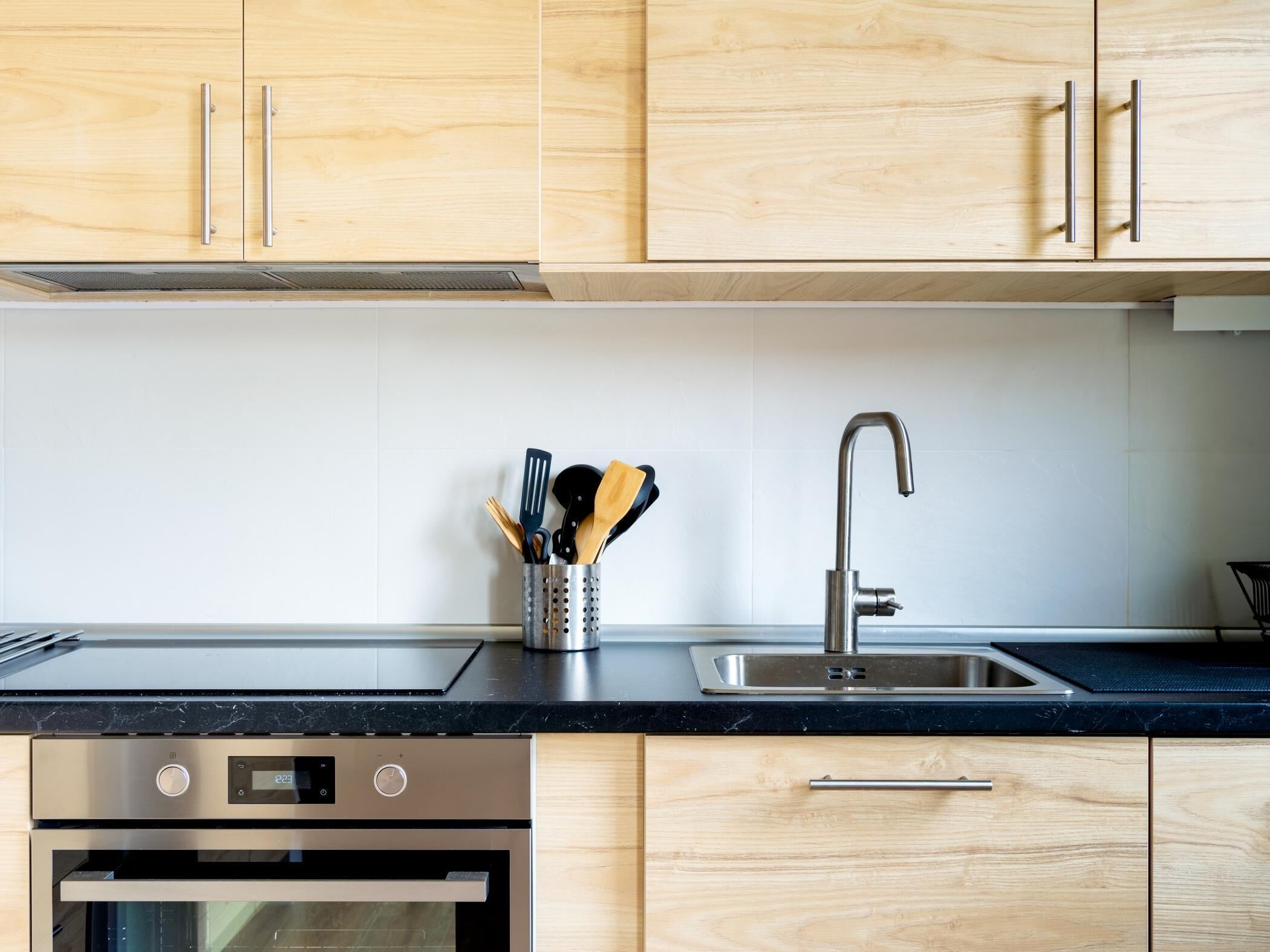 Una cocina moderna con armarios de madera, un lavamanos de acero inoxidable y un horno empotrado.