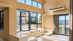 A spacious room with large windows, a ceiling fan, and a view of the outdoors. - Teetara Villa Patong (Patong)