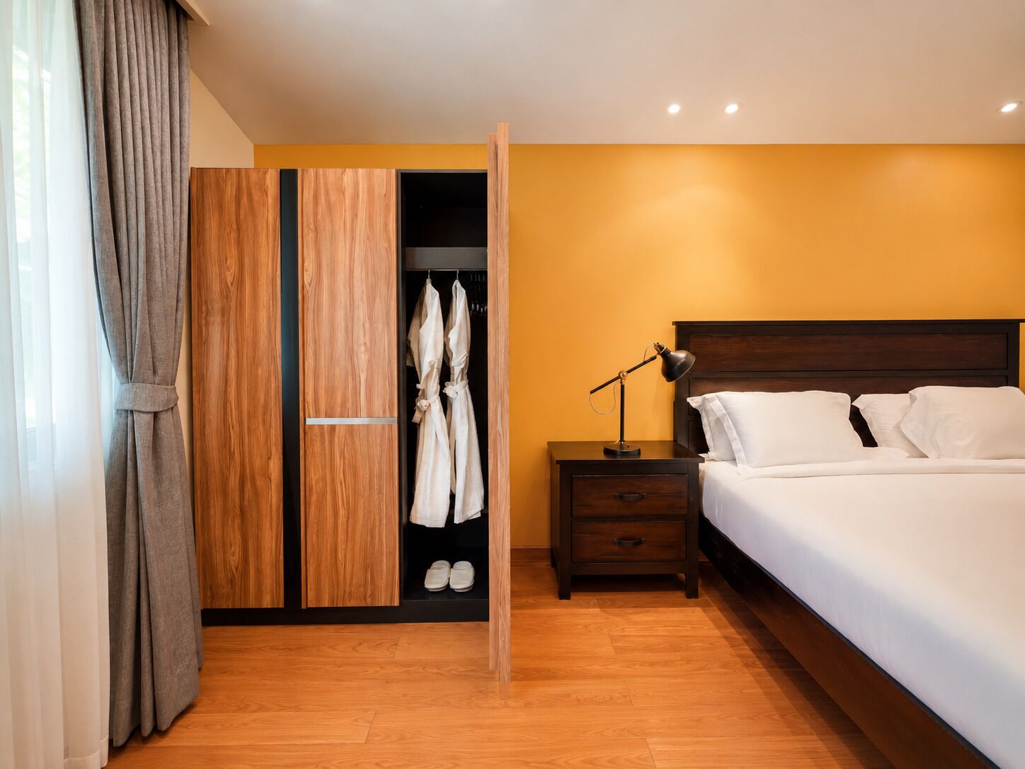 Ein Schlafzimmer mit einem Bett, einem Nachttisch, einem Bademantel und einem Kleiderschrank mit Spiegel.