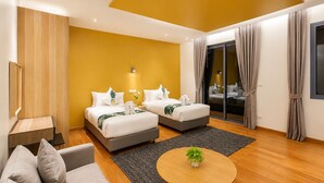 A modern hotel room with two beds, a sofa, a small table, and a sliding glass door to the balcony. - Teetara Villa Patong (Patong)