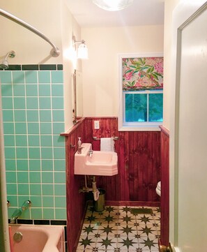 A bathroom with a pink sink, a window with floral wallpaper, and a star-patterned floor.