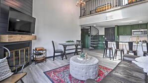 A spacious living area with a fireplace, a television, and a dining set. A staircase leads to an upper level with a balcony. - Pool Access & Balcony: Mtn-View Gatlinburg Condo (Gatlinburg)