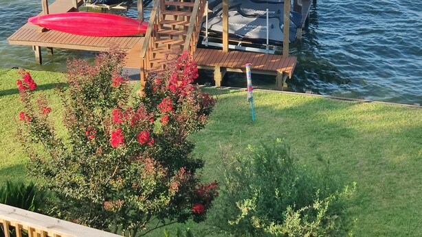 Puinen laituri, joka ulottuu vesistöön, ja jossa on katettu oleskelualue sekä portaat, jotka johtavat ylös tasanteelle.