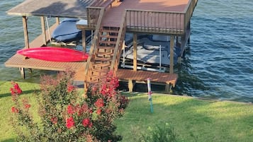 Une jetée en bois s’étendant dans une étendue d’eau, avec un espace de repos abrité et un escalier menant à une plateforme.