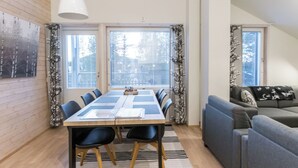 A dining area with a table and chairs, a sofa, and a hanging light fixture.