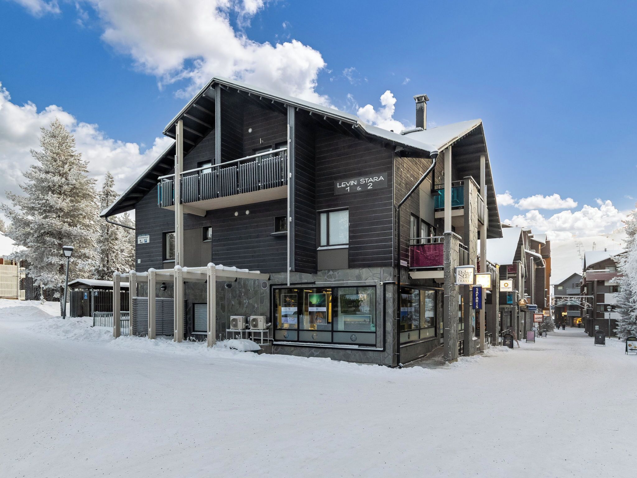 Un bâtiment moderne doté d’un balcon, d’une enseigne indiquant « Levin & Stara 1 & 2 », et d’un magasin avec des portes vitrées.