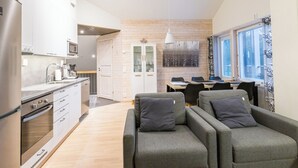 A modern kitchen with white cabinets, a built-in oven, and a dining area with a wooden table and chairs.