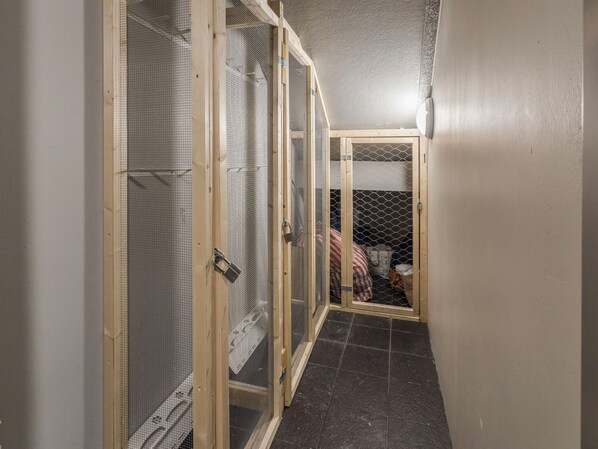 A corridor with three wooden enclosures with mesh doors, leading to a room with a tiled floor.