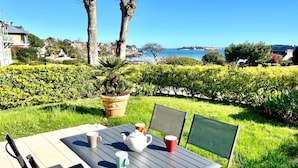 Un patio al aire libre con una mesa y sillas, una planta en maceta y vista al mar.