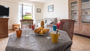 Un comedor con una mesa preparada para dos personas, un televisor y vistas al exterior.