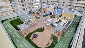 Un immeuble résidentiel à plusieurs étages doté d’une cour intérieure, d’un espace extérieur aménagé pour se détendre et d’une piscine.