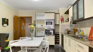 Une cuisine compacte comprenant une table à manger, des chaises, un four encastré et un évier.