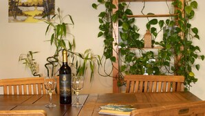 Une table de salle à manger en bois, avec une bouteille de vin et des verres, entourée de chaises.