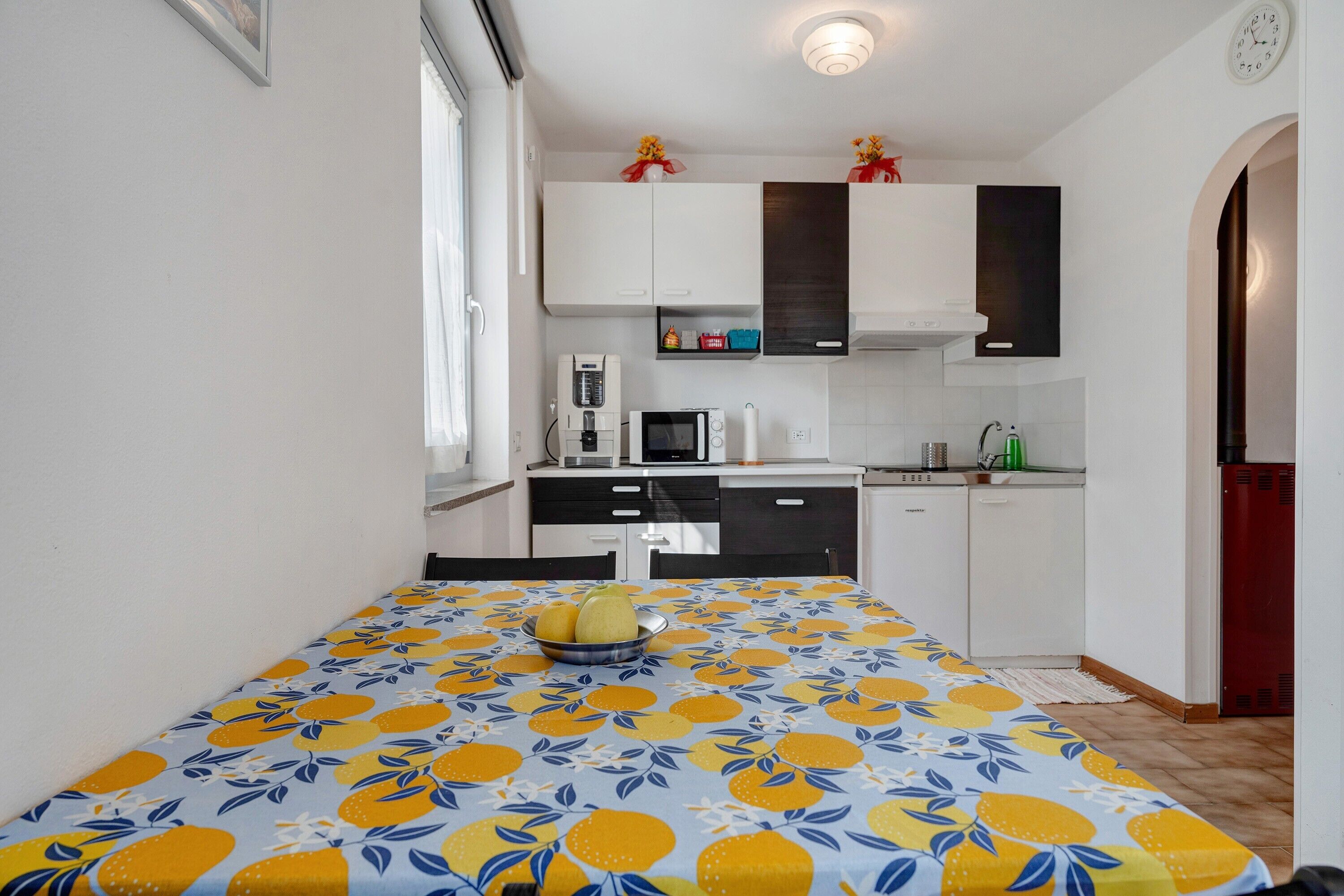 Una cocina compacta con armarios blancos, un microondas, una cafetera y un lavabo.