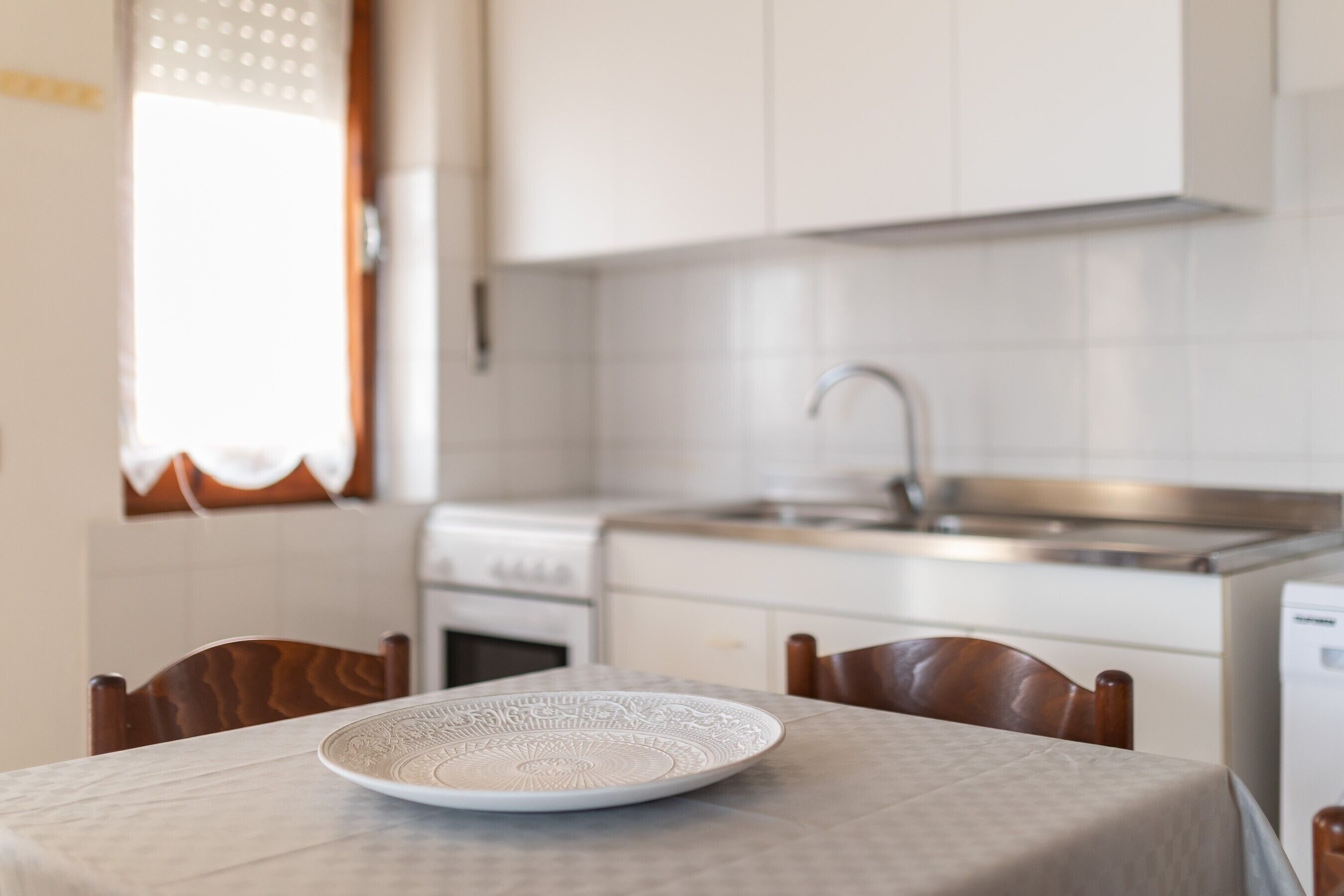 A kitchen with white cabinets, a stainless steel sink, and a white stove.