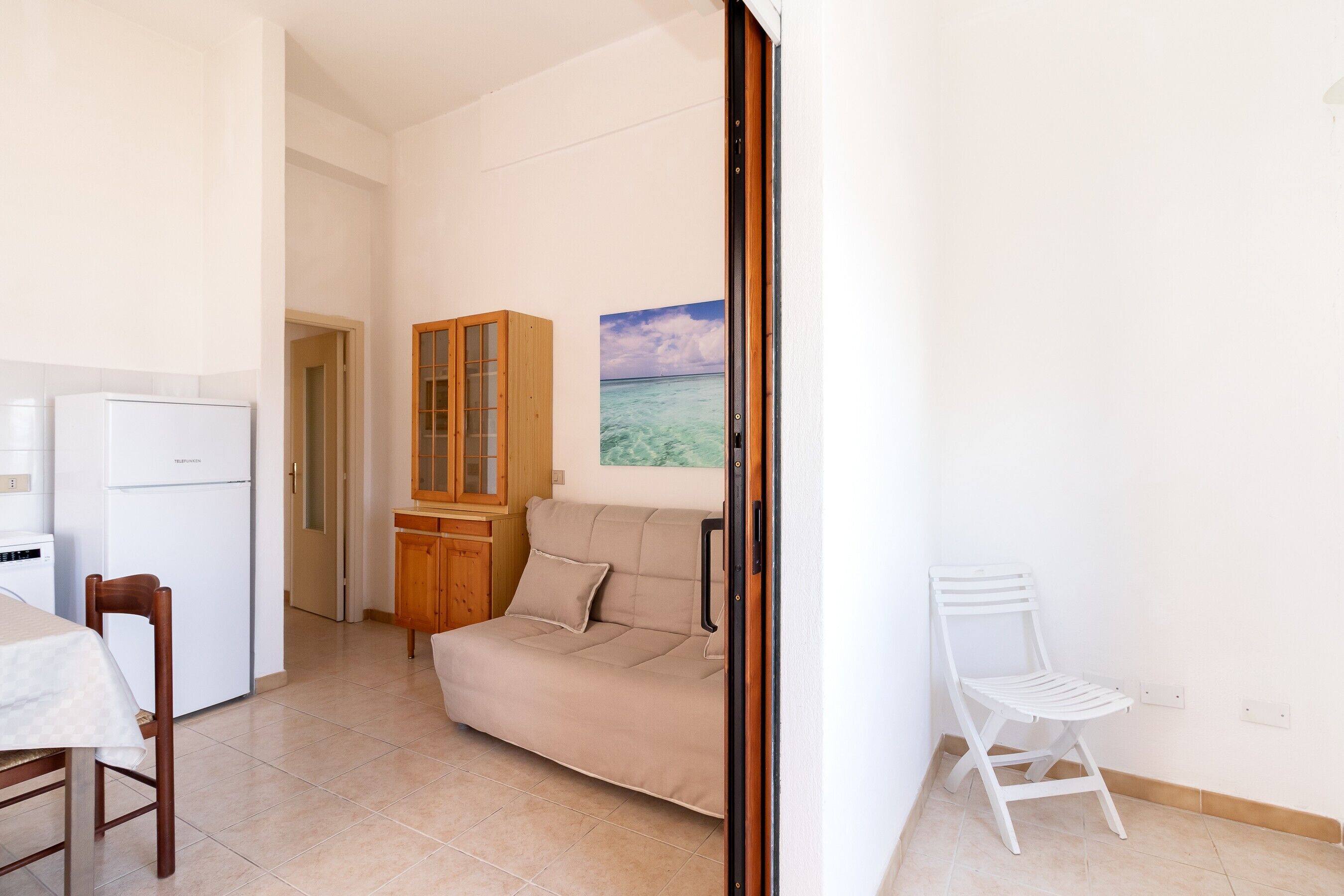 Un espacio habitable compacto con kitchenette, un sofá, una mesa de comedor y una silla.