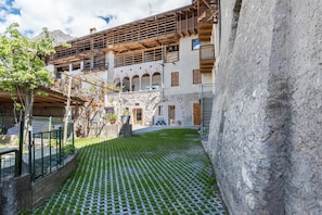 A courtyard with a patterned floor, stone walls, and wooden balconies.