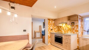 Una cucina moderna con mobili in legno, forno integrato e zona pranzo con una panca e una sedia.