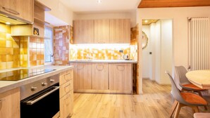 Una cucina moderna con mobili in legno, forno a incasso e zona pranzo con tavolo e sedie.