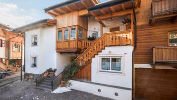 A wooden building with a staircase, a balcony, and a door marked with an 'S'.