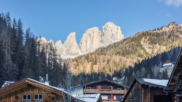 Un rifugio di montagna con architettura in legno, diversi balconi e vista sulle cime rocciose.