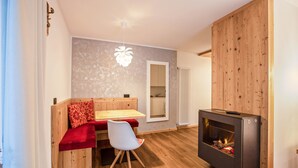 Ein gemütliches Zimmer mit einer Holzbank, einem kleinen Tisch, einem weißen Stuhl und einem Kamin.