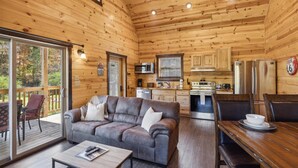 A cozy cabin interior with a wooden interior, a sofa, a dining table, and a kitchen area.