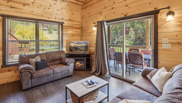 A cozy wooden cabin interior with a sofa, a coffee table, and a fireplace.