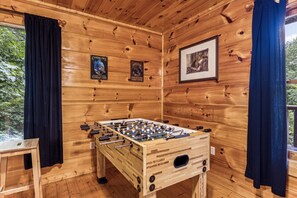 Relax in this inviting room with a foosball table and framed artwork, surrounded by rustic charm.
