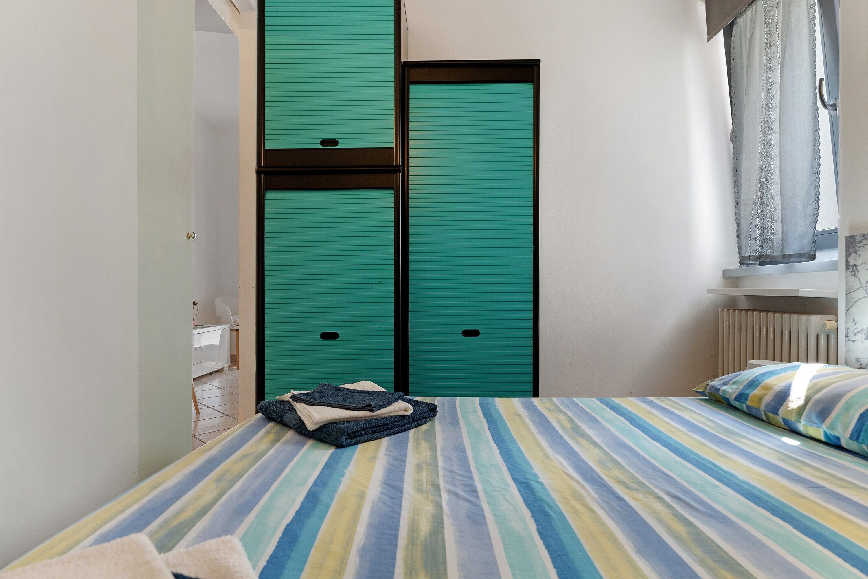A room with a bed, a window with curtains, and a door with a lock.