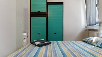 A room with a bed, a window with curtains, and a door with a lock.