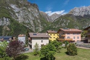 Ein Wohngebiet mit Häusern, einem Auto und Bergen im Hintergrund.
