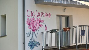 A building with a mural of pink flowers and the word 'Ciclamino' on the wall.
