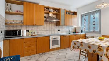 Una cocina con armarios de madera, un microondas, un horno y una mesa de comedor con mantel de girasoles.