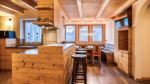 Ein Holzinterieur mit Kücheninsel, Barhocker und Essbereich.