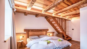 Ein Schlafzimmer mit einem Holzbett, einem Nachttisch, einer Lampe und einer Holztreppe.