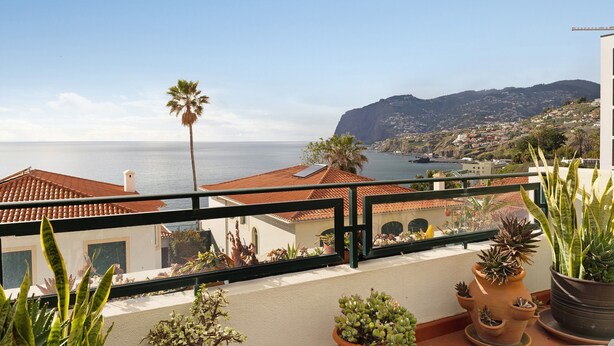 A balcony with potted plants, a view of the sea, and a mountain in the background. - Luzias Apartment with Sea View, Wi-Fi & Balcony (Funchal)