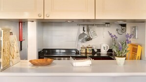 A kitchen with white cabinets, a stainless steel range, a coffee maker, and a potted plant. - Luzias Apartment with Sea View, Wi-Fi & Balcony (Funchal)