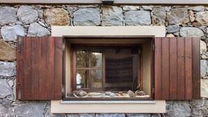 A stone wall with a window featuring wooden shutters, a lantern above, and pinecones on the sill. - Vacation Chalet "The Perfect Cottage" with Mountain View & Wi-Fi (São Vicente)
