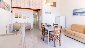 A modern kitchen with a dining area, a sofa, and artwork on the walls. - Apartment "Vista Corsica" on Isola Rossa with Sea View & Terrace (Isola Rossa)