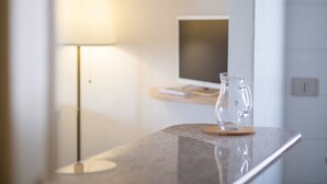 Een badkamer met een marmeren aanrechtblad, een glazen kruk, een lamp en een monitor op een standaard.