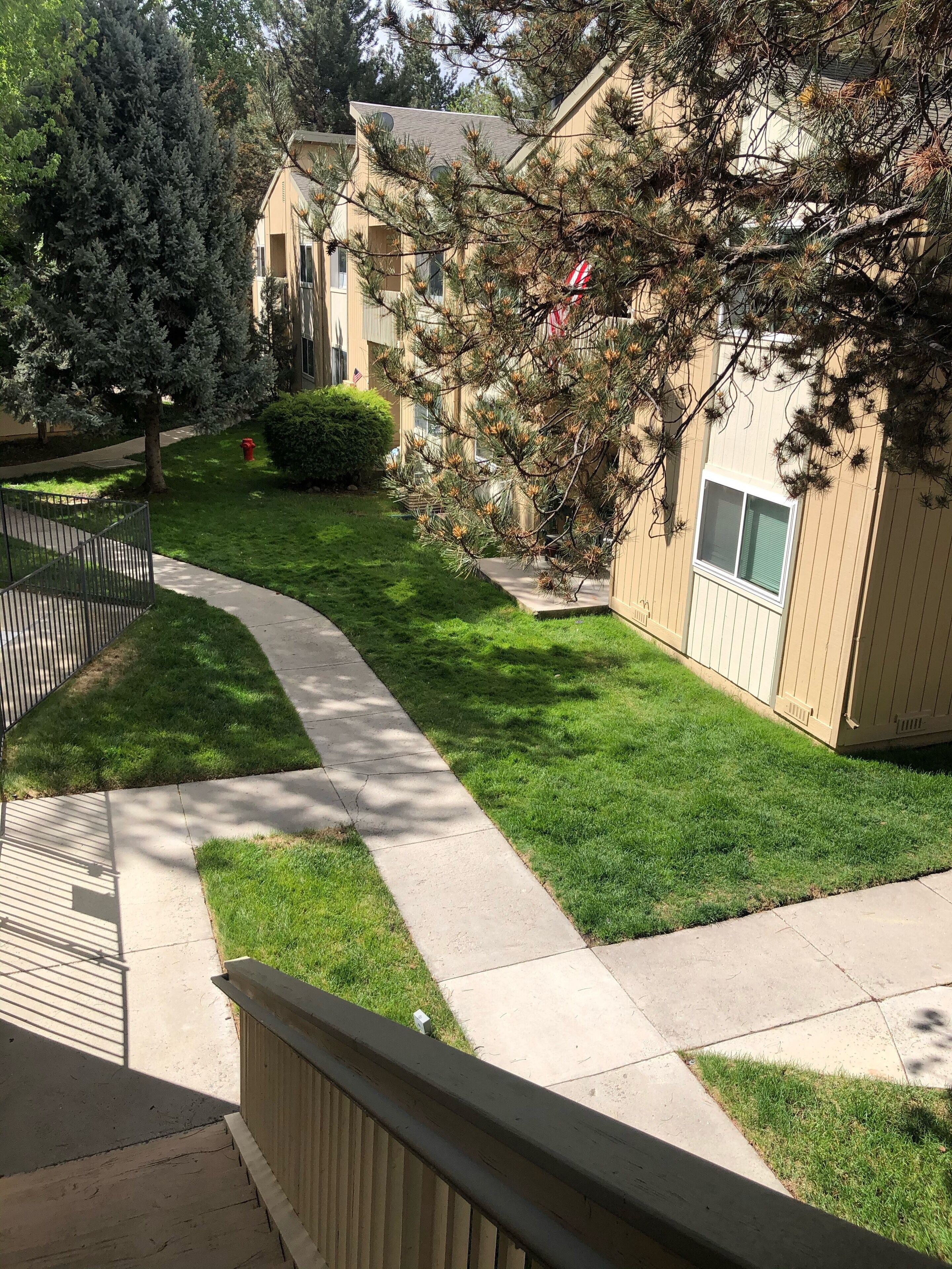 Uma área residencial com gramado bem cuidado, calçada e um edifício de fachada bege.
