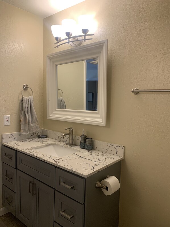 A bathroom with a white vanity, a mirror, a towel ring, a towel, a toilet paper holder, and a towel rack. - On the beautiful Truckee River, walk to town and all attractions (RENO)